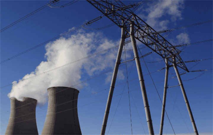 Nuclear plant cooling towers with power transmission pylons under blue sky