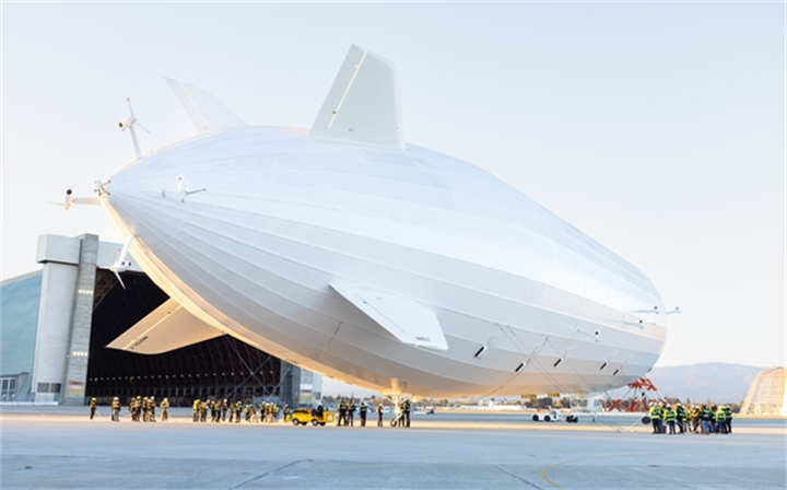 Large modern white cargo airship parked on tarmac with ground crew, alternative low-carbon aerial transport