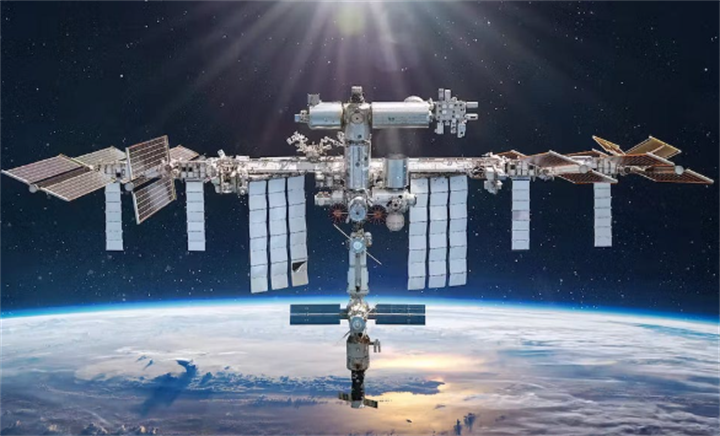 International Space Station (ISS) orbiting above Earth’s cloud-covered atmosphere with sunlight beaming from space, core platform for on-orbit manufacturing and space servicing research