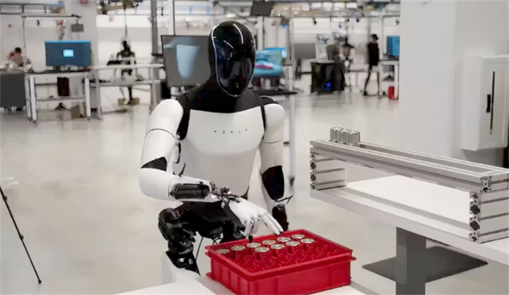 Tesla Optimus humanoid robot performing component sorting and handling tasks inside Tesla’s industrial R&D workshop
