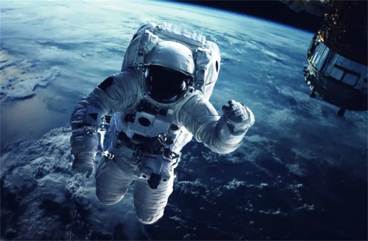 Astronaut performing extravehicular spacewalk above Earth’s cloud layer, representing aerospace & space industry technology